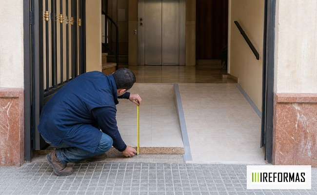 portal accesible con técnico midiendo el umbral de entrada de un edificio residencial